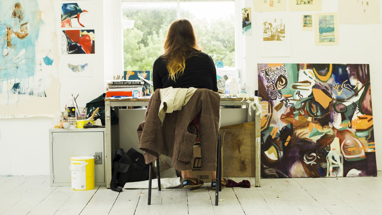 Student sitting in front of a window surrounded by artwork