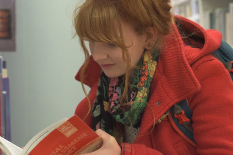 woman in red coat reading a book