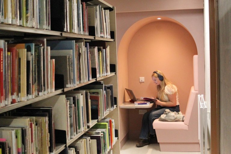 student wearing headphones sitting in a solo study booth