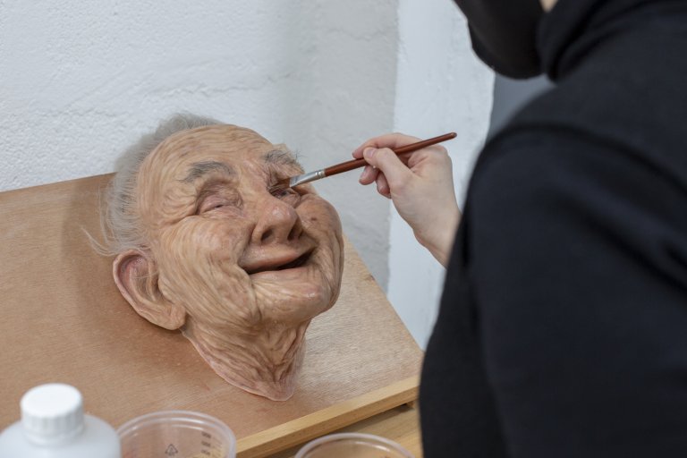 painting a prosthetic face of an old person