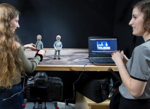 desk with two students with stop gap animation characters and laptop